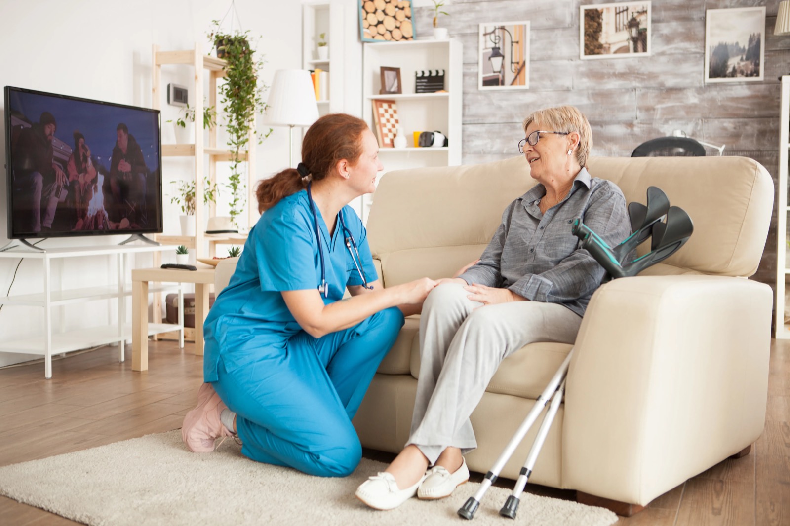 Caregiver in blue uniform talking with senior woman in her home